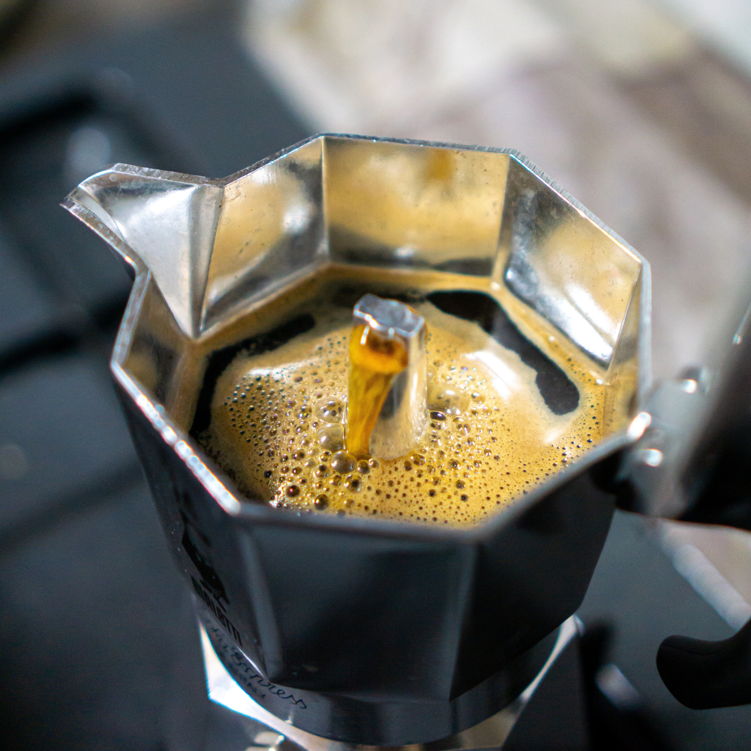 Stainless steel Moka Pot brewing rich coffee from Huehuetenango, Guatemala on a black table. A smooth and bold filter coffee made from single-origin beans.